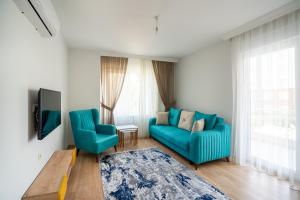 a living room with two blue chairs and a tv at River Park Residence Lara in Antalya