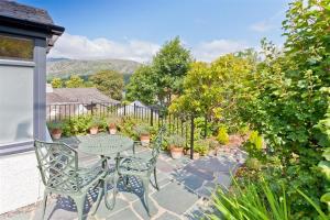 a patio with a table and chairs and plants at Badger's Cottage with stunning lake & mountain views in Coniston