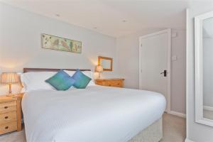 a bedroom with a large white bed with blue pillows at Badger's Cottage with stunning lake & mountain views in Coniston