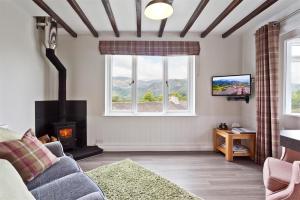 a living room with a couch and a fireplace and a tv at Badger's Cottage with stunning lake & mountain views in Coniston