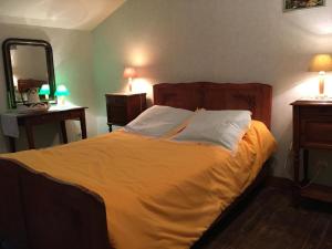 a bedroom with a large bed with yellow sheets and a mirror at Le balét in Asnois