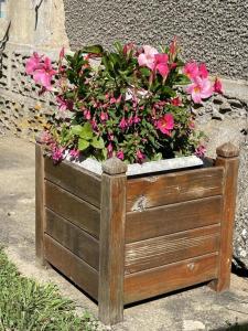 a wooden planter with pink flowers in it at Le balét in Asnois +2 photos