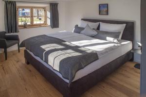 a bedroom with a large bed with a chair and a window at Geigelstein Chalets in Unterwössen