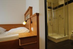 a bedroom with a bed and a glass shower at Bräuhaus Ummendorf in Ummendorf-Biberach