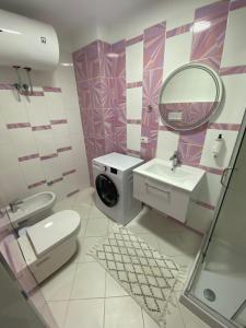 La salle de bains est pourvue de toilettes, d'un lavabo et d'un miroir. dans l'établissement Merville Apartment 6, à Durrës