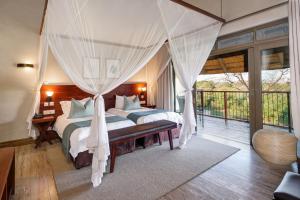 a bedroom with two beds and a balcony at Ilala Lodge Hotel in Victoria Falls