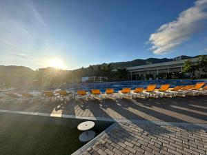 a group of chairs and a pool with the sun in the background at Oceanami Villa Long Hải - Vũng Tàu in Long Hai