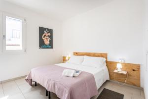 a white bedroom with a bed with a pink blanket at Appartamenti Rocca 'Ja in Castelsardo