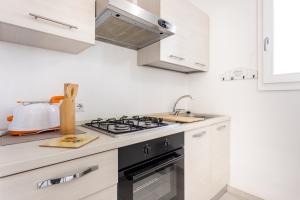 eine weiße Küche mit Herd und Spüle in der Unterkunft Appartamenti Rocca 'Ja in Castelsardo