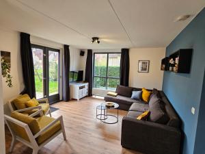 a living room with a couch and two chairs at 7 person House with swing, firepit, hammock, garden, swimming lake, child friendly, in- and outside playground, and great coffee in Ewijk