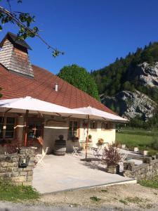 une maison avec un parasol et des chaises devant elle dans l'établissement L'arbre à chapeaux, à La GrandʼCombe-Châteleu