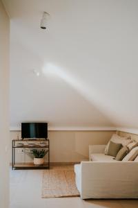 uma sala de estar branca com um sofá e uma televisão em Apartamentos Poniente - Mares em Torre del Mar