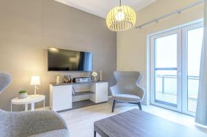 a living room with a tv and two chairs and a table at Ferienwohnung Ostseeblick mit Balkon in Wustrow