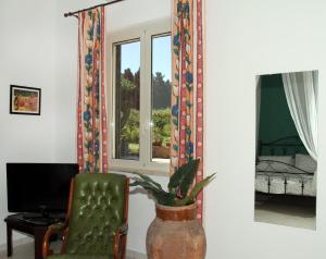 ein Wohnzimmer mit einem grünen Stuhl und einer Vase mit einer Pflanze in der Unterkunft Tenuta Piana 2 con accesso diretto al mare in Caronia