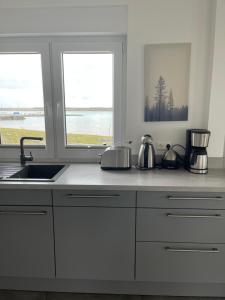 a kitchen with white cabinets and a sink and two windows at Ferienhaus SEE & Ferienhaus SEEBLICK in Neukieritzsch