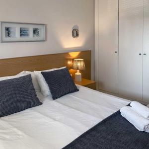 - une chambre avec un lit blanc et des oreillers noirs et blancs dans l'établissement Apartamento en la playa de Valdelagrana, à El Puerto de Santa María