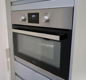 a microwave oven with a clock on top of it at Stylish Studio Apartment, ensuite, kitchenette in Twickenham