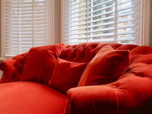 un sofá rojo sentado frente a una ventana en Stylish Studio Apartment, ensuite, kitchenette en Twickenham