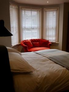 a bedroom with a large bed and a red chair at Stylish Studio Apartment, ensuite, kitchenette in Twickenham