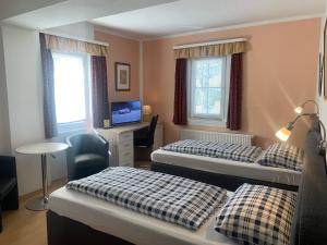 a room with two beds and a desk with a television at Zum weißen Ross in Nidda
