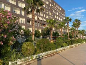 a building with palm trees and bushes in front of it at Merville Apartment 6 in Durrës
