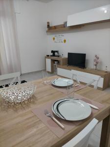 einem Holztisch mit zwei weißen Tellern und Besteck in der Unterkunft Holiday House Chiara in SantʼAntìoco