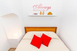 Una cama con almohadas rojas y un cartel que lee siempre lo bueno en Studios Anna, en Rovinj