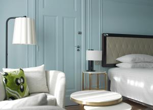 パリにあるパリス マリオット オペラ アンバサダー ホテルのベッドルーム1室(ベッド1台、椅子、ランプ付)