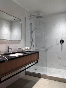 a bathroom with a shower and a sink and a mirror at Paris Marriott Opera Ambassador Hotel in Paris