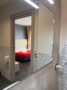 un bagno con una camera da letto con letto rosso e specchio di B&B Margherita a Messina