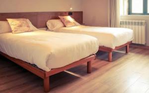 2 Betten in einem Zimmer mit Holzböden in der Unterkunft O Lagoeiro in A Estrada