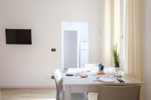 a white dining room table with two chairs and a television at Residence dell'Abbadia by Studio Vita in Bologna