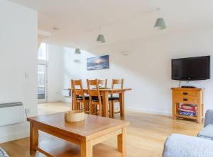 a living room with a table and a tv at House 6 Goldcroft - Walk to Beach & Village, Pet-friendly & hottub in Porthtowan