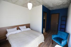 a bedroom with a white bed and a blue chair at Aragvispiri wine cellar in Aragvispiri