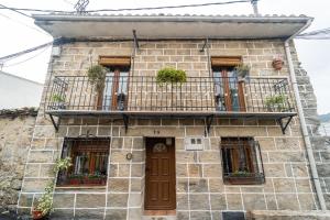 Bustarviejo的住宿－La Casa del Señor Perez，带阳台和门的石头房子