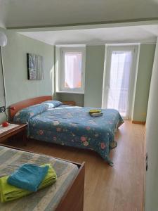 1 dormitorio con 2 camas, mesa y 2 ventanas en Il nido di Simone, en Castagnito