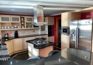 Luxury Canterbury Holiday Home Sleeps Ten Wifi في كانتربيري: مطبخ مع موقد وثلاجة