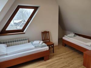 ビャウカにあるU Juhasa Miętówkaのベッド2台と窓が備わる屋根裏部屋です。