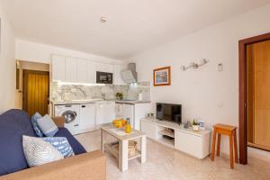 a living room with a blue couch and a kitchen at SeaBliss Beach of Dunes, Terrace and Pool! in San Bartolomé de Tirajana
