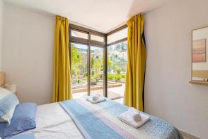 a bedroom with a bed with yellow curtains and a window at SeaBliss Beach of Dunes, Terrace and Pool! in San Bartolomé de Tirajana +25 photos