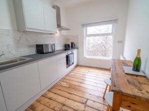 a kitchen with white cabinets and a wooden floor at Pass the Keys Beautiful flat near Nottingham city with parking in Nottingham