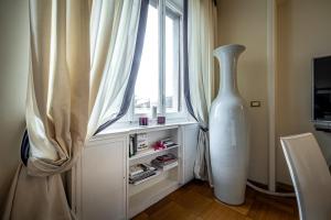 YID D'Azeglio luxury apartment في فلورنسا: وجود مزهرية بيضاء كبيرة بجوار النافذة