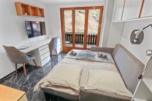 a bedroom with a bed and a desk and a window at Joli studio au centre de Nendaz in Nendaz
