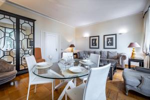 YID D'Azeglio luxury apartment في فلورنسا: غرفة معيشة مع طاولة زجاجية وكراسي بيضاء