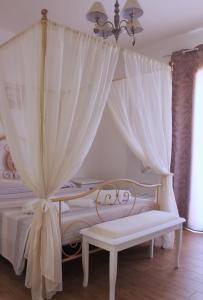 a bedroom with a white canopy bed with a bench at Guest House Bellavista Nebida in Nebida