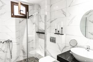 a white bathroom with a sink and a shower at Vacation house with a panoramic sea view and forest in Polychrono