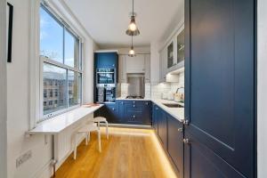 a kitchen with blue cabinets and a window at Finest Retreats - Hill Rise in Richmond
