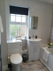 een badkamer met een wastafel, een toilet en een raam bij Boutique Abode - With Hot Tub in Chester