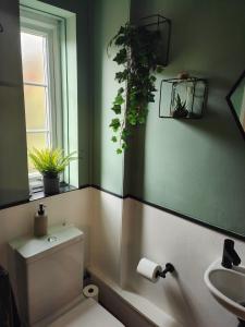 a bathroom with a toilet and a sink with plants on the walls at Boutique Abode - With Hot Tub in Chester