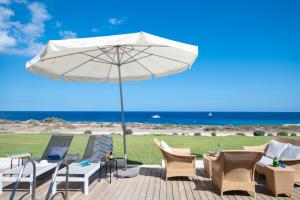 a patio with chairs and an umbrella and the ocean at Jasmine Sea Front Villa in Protaras